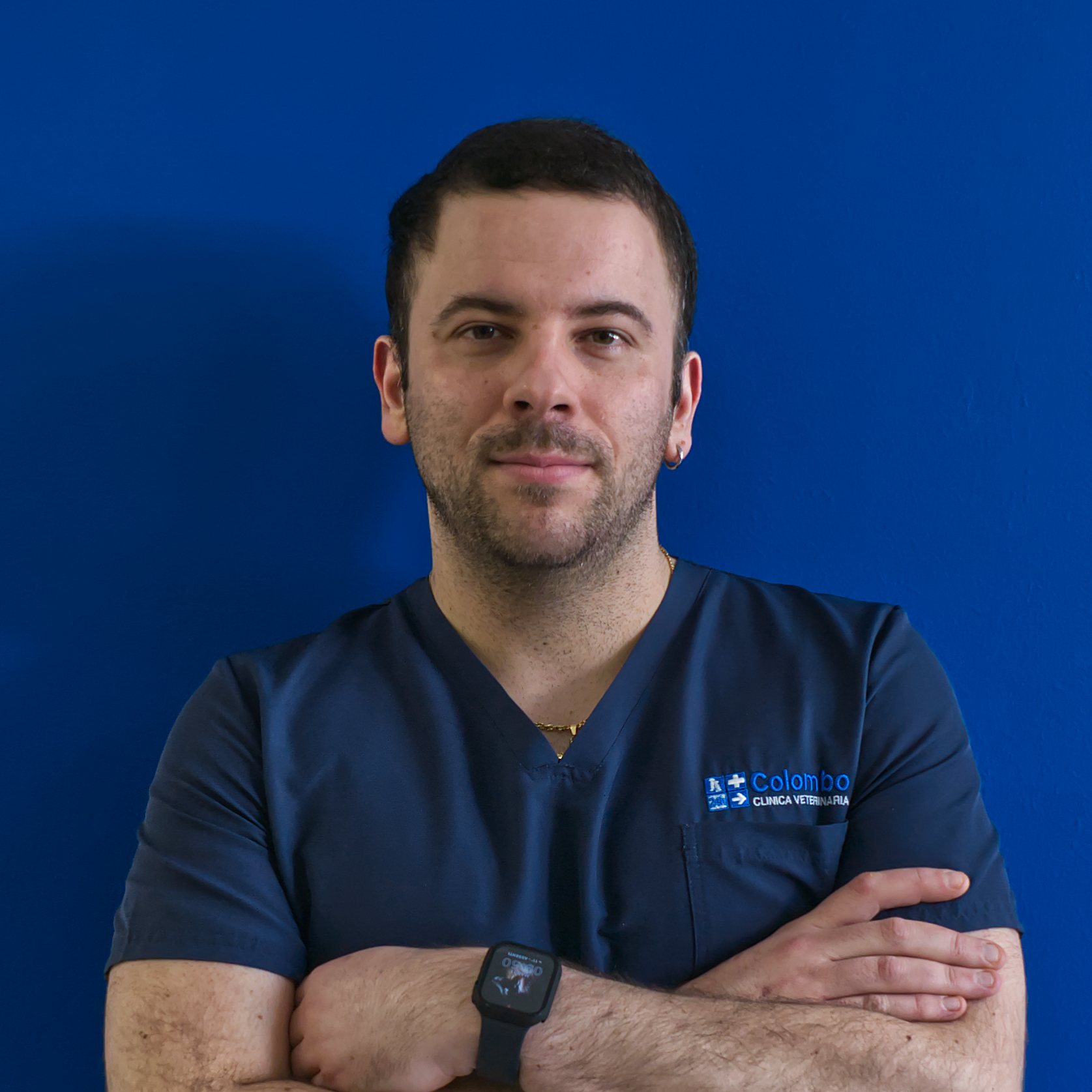 Una persona del team Il sta in piedi con sicurezza su uno sfondo blu, indossando una maglietta blu navy con la scritta 